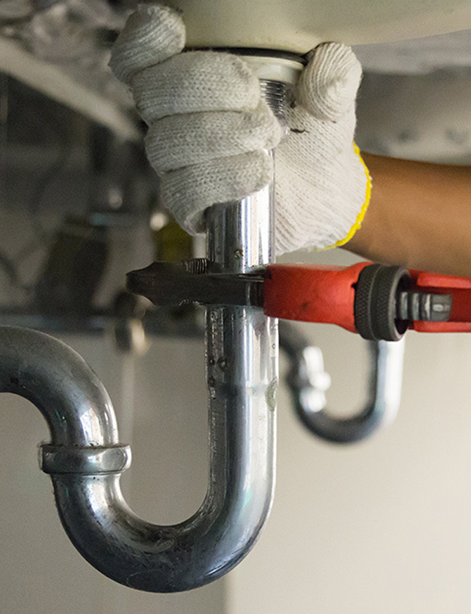 Plumber tightening pipe fittings with wrench